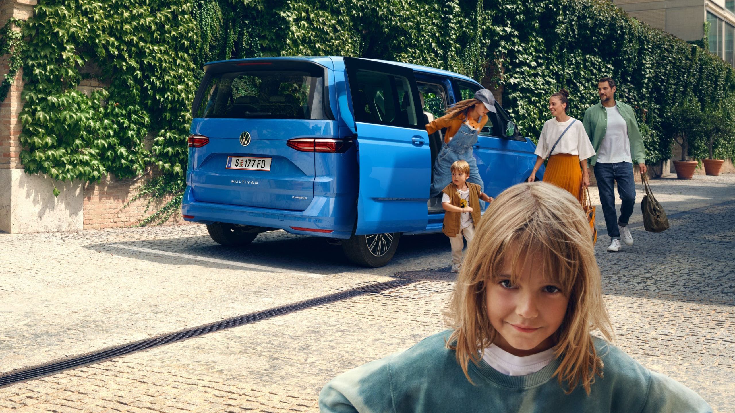 Ein Mädchen steht vor dem neuen VW Multivan T7 2021 und schaut trotzig in die Kamera.