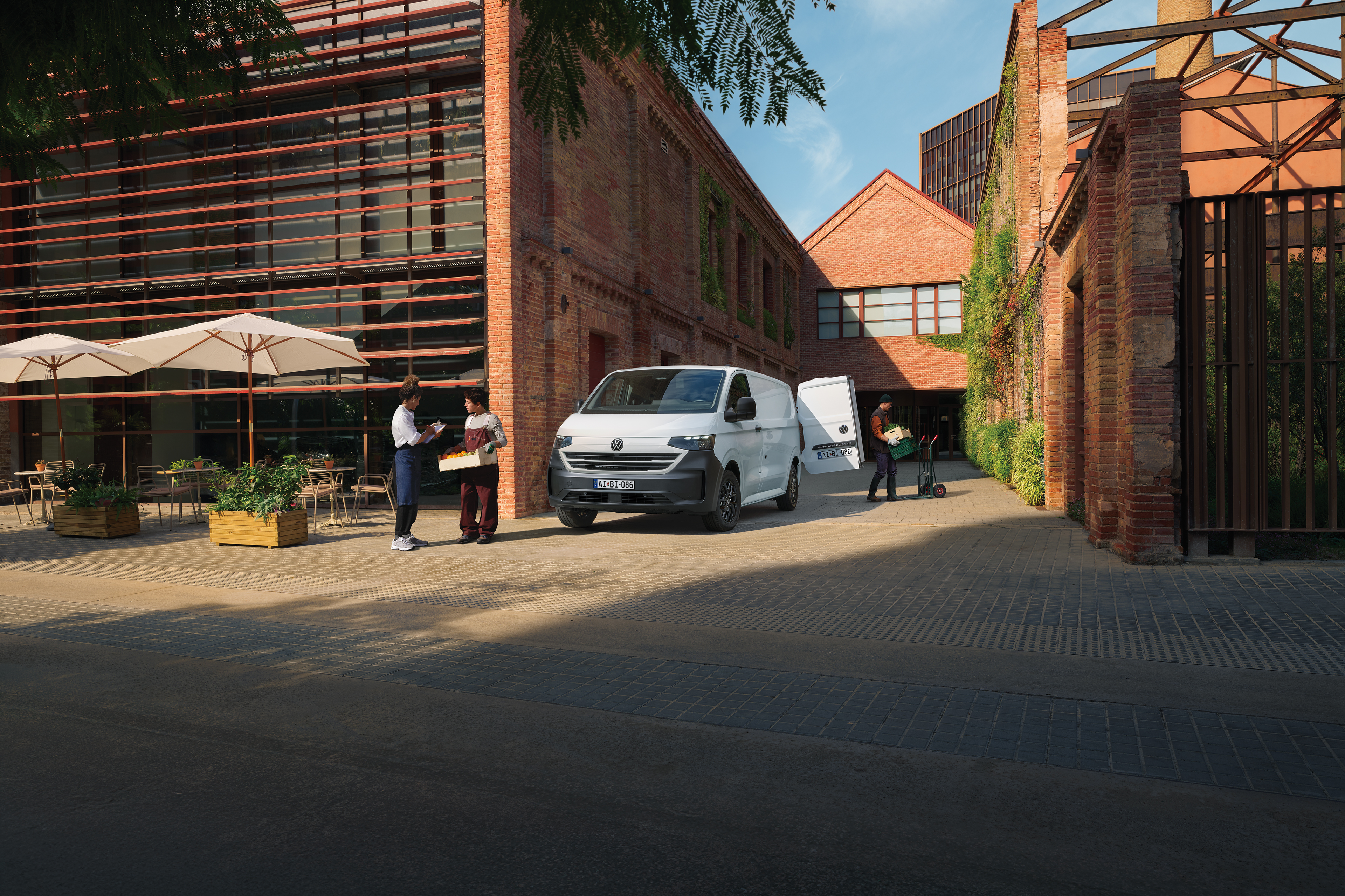 VW Transporterből pakol ki a postás egy kellmes utcán