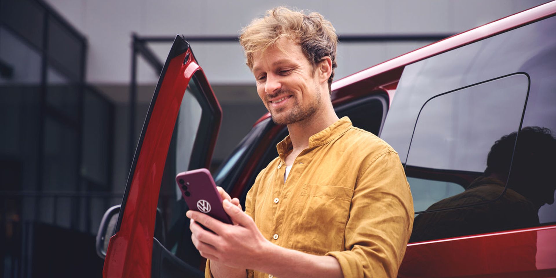 Férfi VW logós mobiltelefont fog a kezében