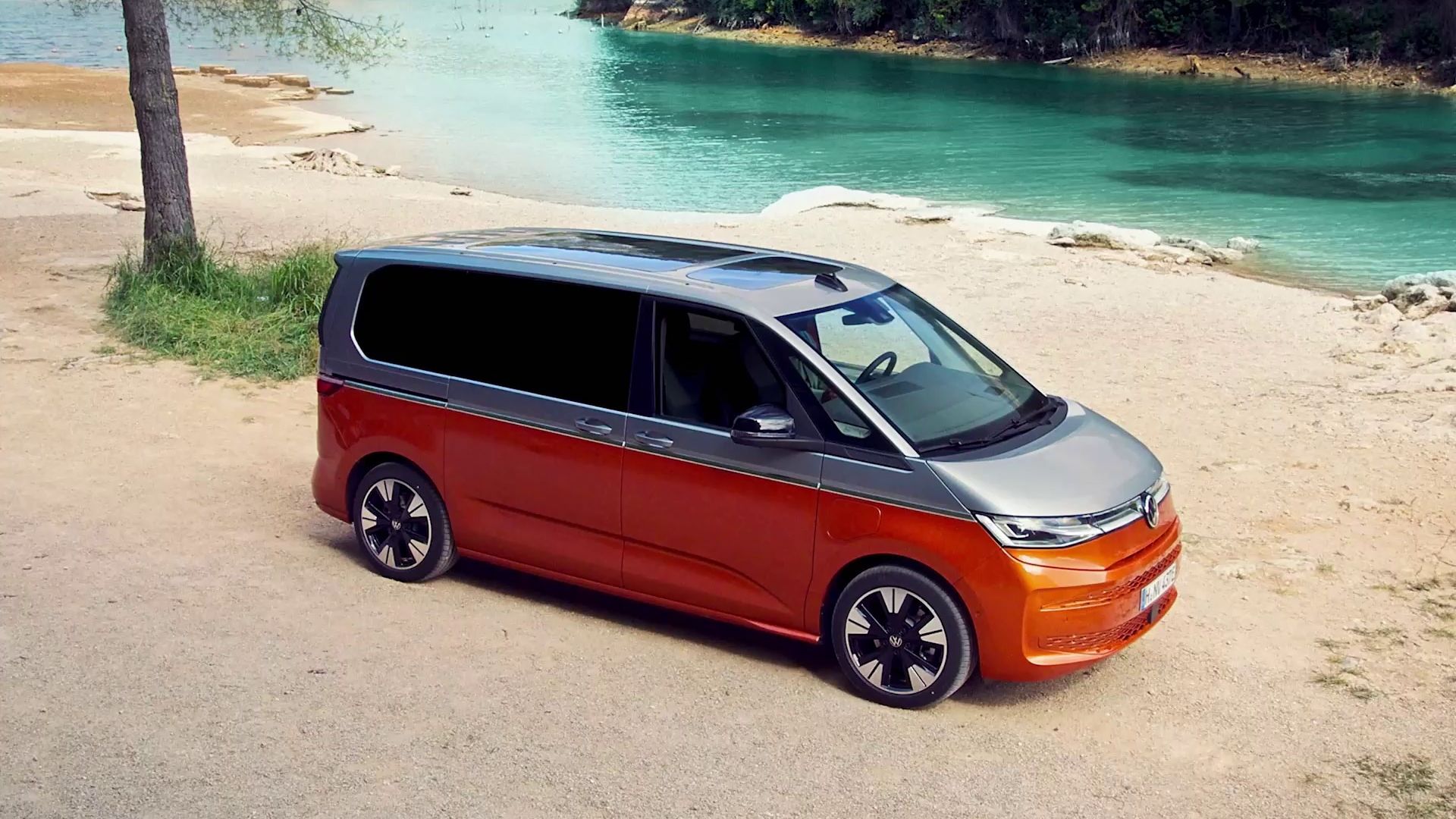 Der neue VW Multivan T7 2021 steht auf einem Platz vor einem Fluss.