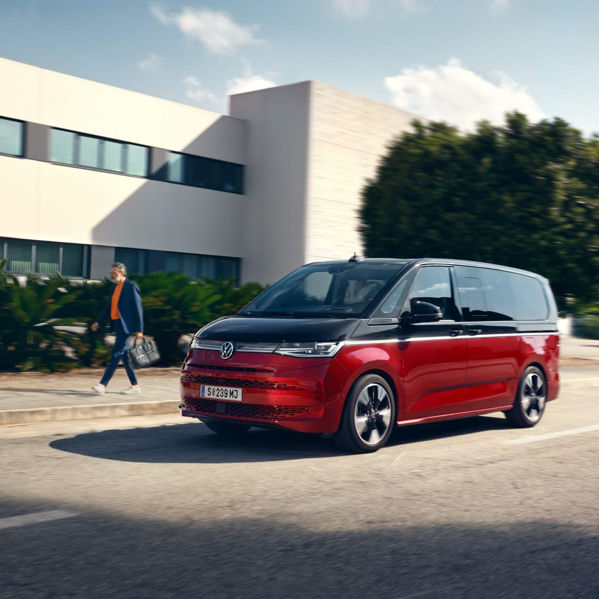 Der neue VW Multivan Style T7 fährt auf einer Straße neben einem Mann. 