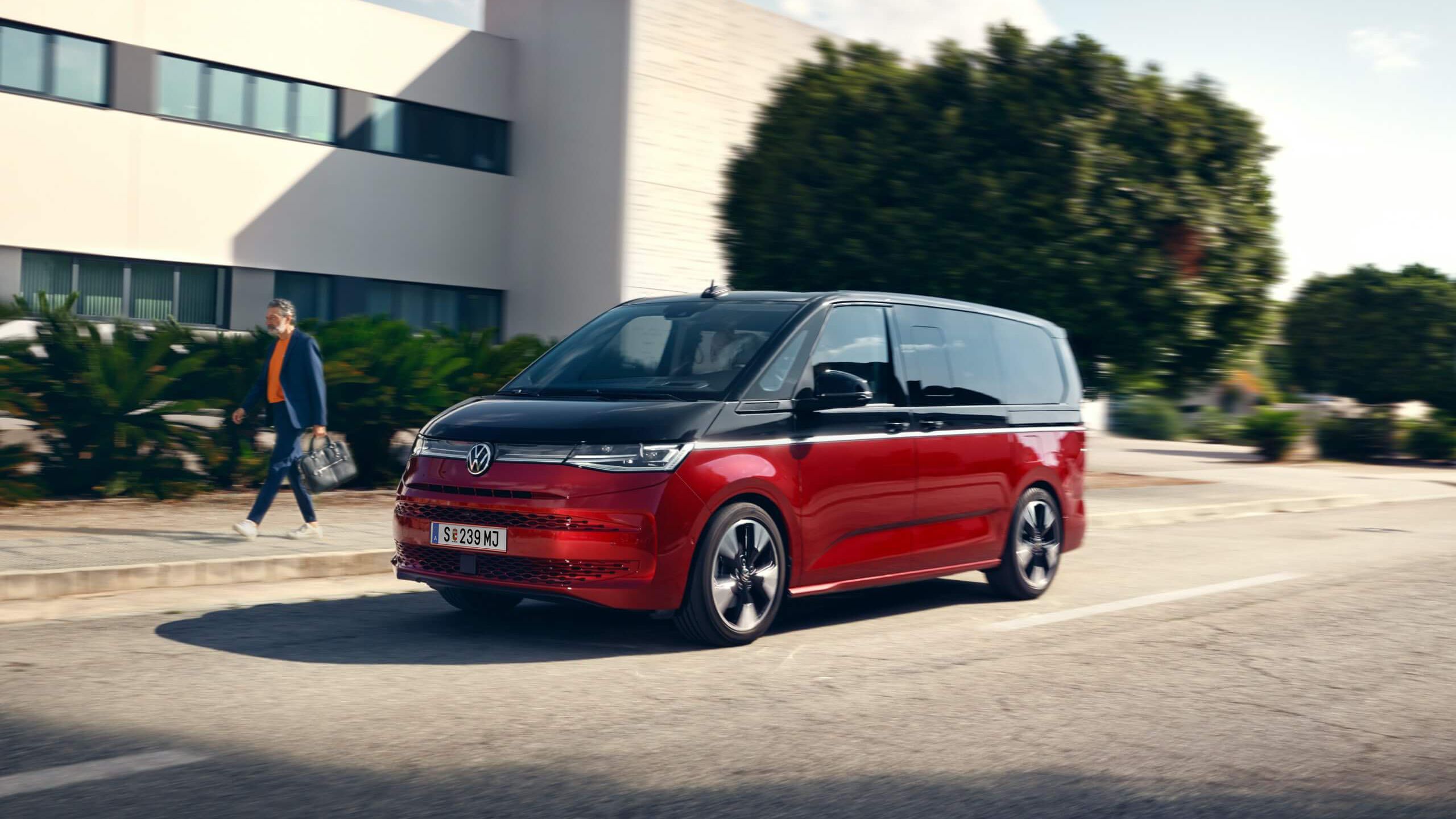Der neue VW Multivan Style T7 fährt auf einer Straße neben einem Mann. 